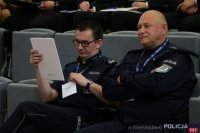 przedstawia dwóch umundurowanych policjantów siedzących na widowni na auli podczas konferencji