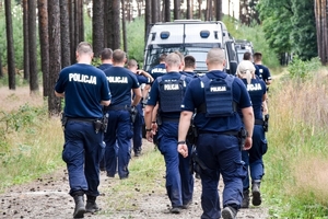 grupa policjantów w akcji poszukiwawczej w lesie